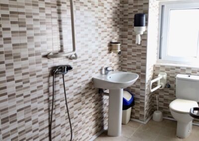 Baño completamente accesible en Residencia Pirineos, residencia de mayores en Zaragoza, con suelo antideslizante, barra de apoyo y espacio para silla de ruedas.