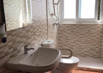 Baño adaptado en Residencia Pirineos, residencia de mayores en Zaragoza, con accesos seguros, barra de apoyo y ducha a ras de suelo.